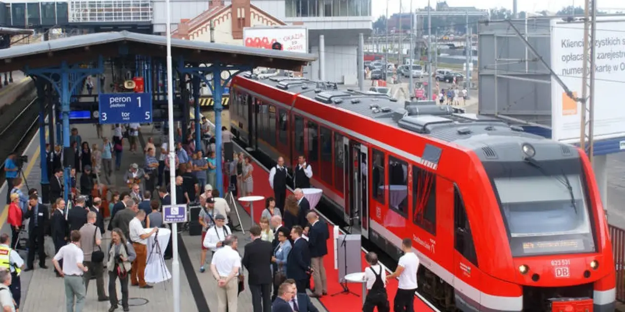 Czerwony pociąg na peronie dworca Szczecin Główny, gotowy do podróży do Berlina. Ludzie czekają na platformie.