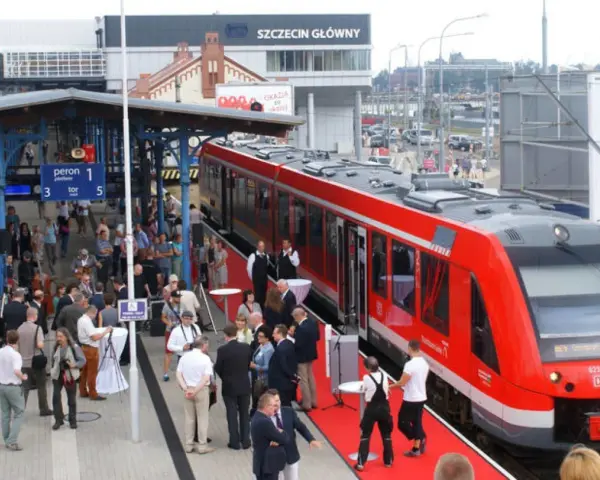 Czerwony pociąg na peronie dworca Szczecin Główny, gotowy do podróży do Berlina. Ludzie czekają na platformie.