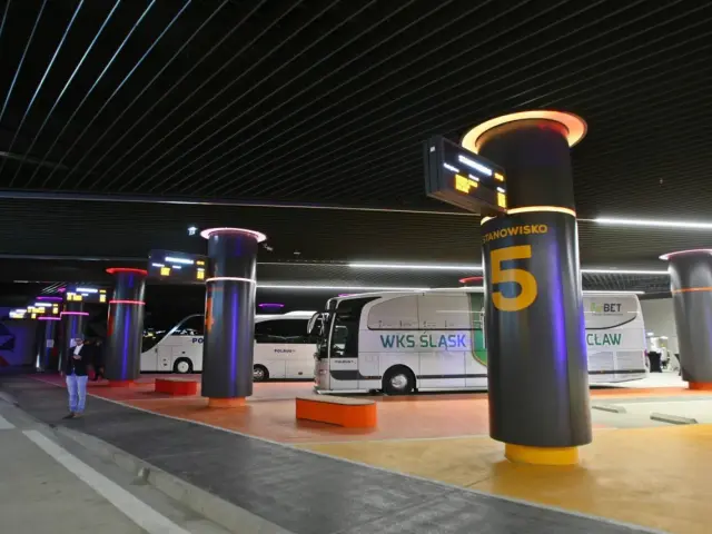 Nowoczesny dworzec autobusowy, gdzie polski bus Wrocław skąd odjeżdża, z podświetlanymi słupami i tablicami informacyjnymi.