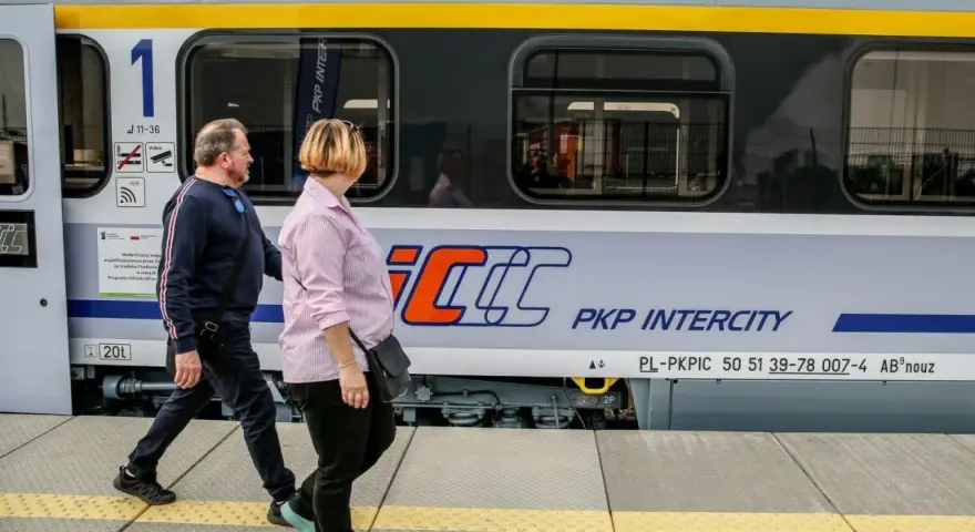 Para podróżuje obok pociągu PKP Intercity, który może zabrać ich z Rzeszowa do Krakowa.