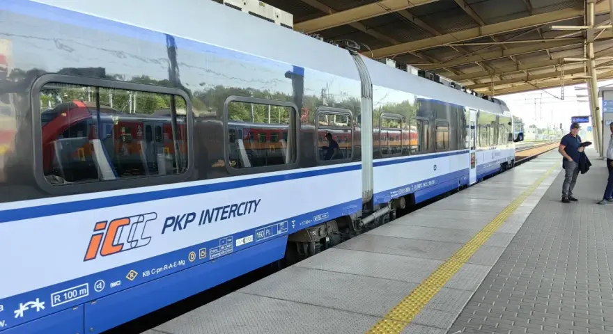 Pociąg PKP Intercity na peronie, z widocznymi oknami i logo przewoźnika.