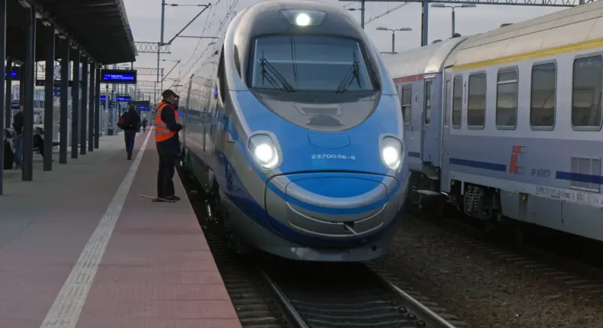 Pendolino Warszawa-Kraków na peronie. Maszynista w kamizelce odblaskowej czeka na pasażerów.