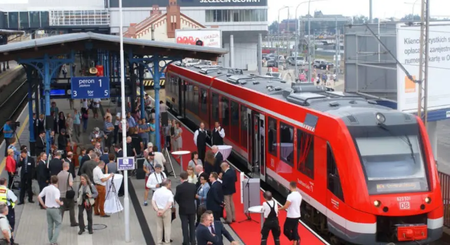 Czerwony pociąg na peronie dworca Szczecin Główny, gotowy do podróży do Berlina. Ludzie czekają na platformie.