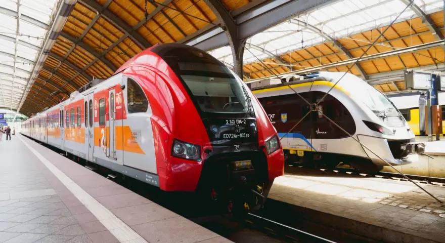 Dwa nowoczesne pociągi, czerwony i srebrny, czekają na pasażerów na dworcu. To idealny pociąg do poznania nowych miejsc.