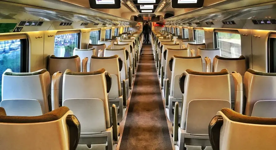 Wnętrze pustego wagonu. Widok na rzędy siedzeń, idealne na podróż pociągiem Kraków - Zakopane.