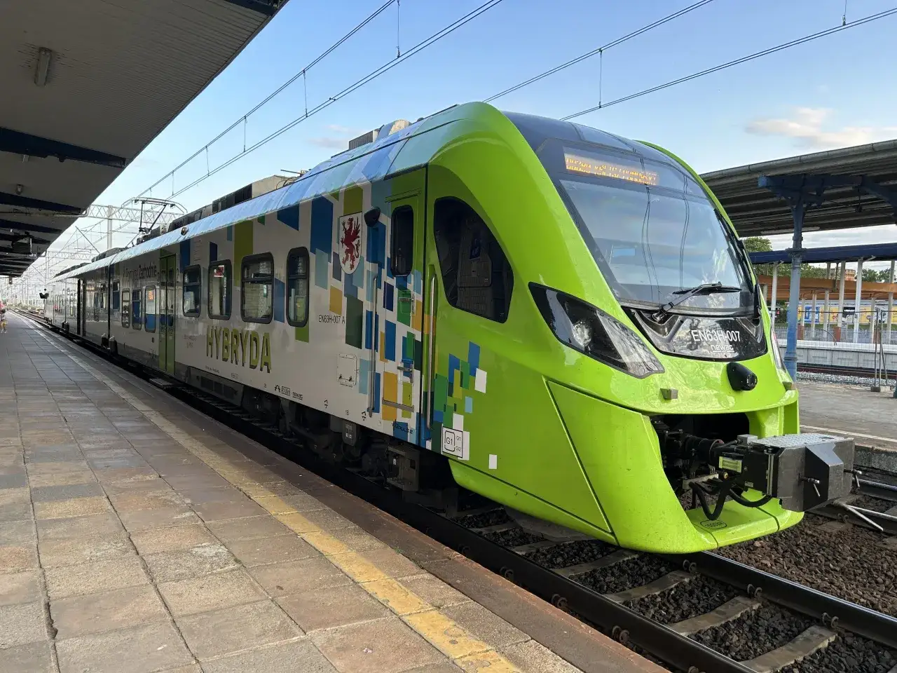Nowoczesny, zielony pociąg hybrydowy EN63H-007 czeka na pasażerów na peronie. Niedługo ruszy w podróż z Świnoujścia do Szczecina.