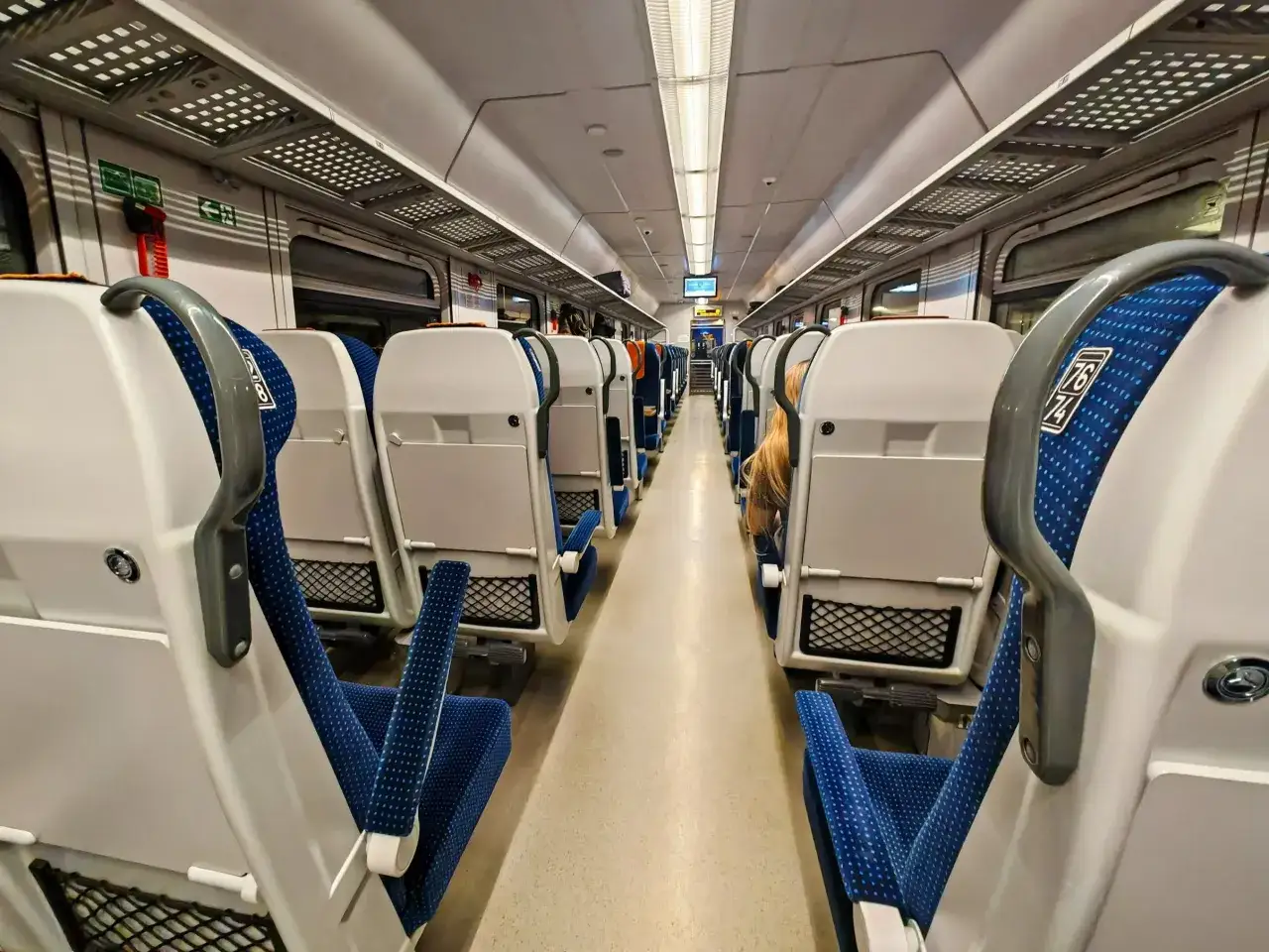 Wnętrze pociągu Pendolino na trasie Warszawa-Zakopane. Puste siedzenia z niebieskimi obiciami czekają na pasażerów.