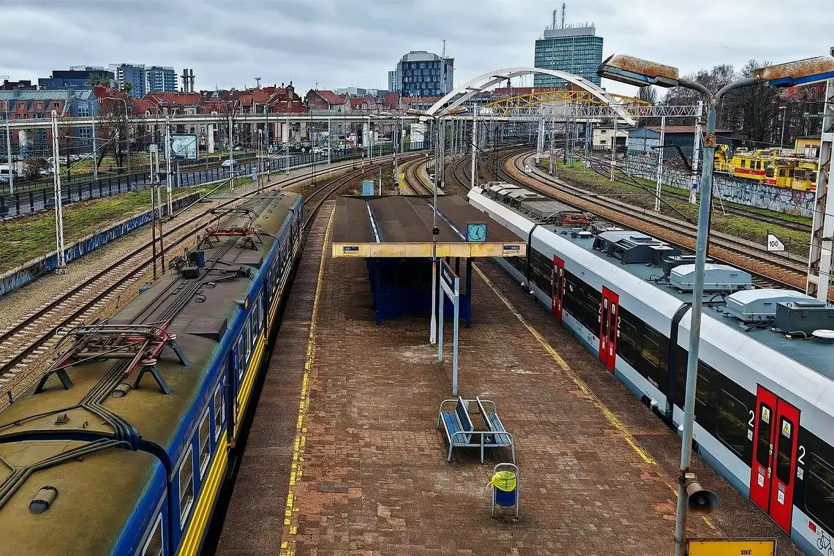 Dwa pociągi na stacji, jeden niebiesko-żółty, drugi biało-czerwony. Może to właśnie ten pociąg Olsztyn Gdańsk?