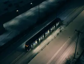 Nocny pociąg z Warszawy do Budapesztu mknie przez ośnieżone tory, oświetlając zimowy krajobraz.